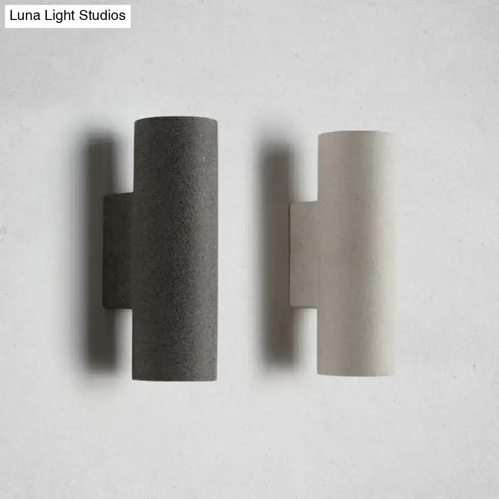 Two minimalist concrete wall sconces in dark gray and light beige with compact fixture height for stair use