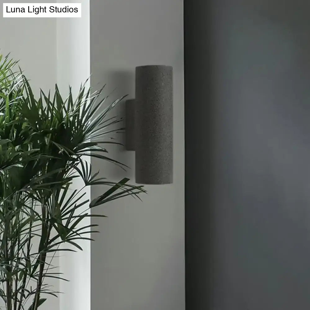 Minimalist gray cylindrical wall sconce with textured concrete finish and compact fixture height for stair lighting