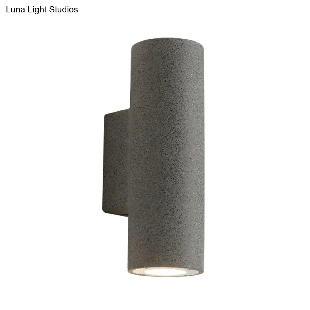 Gray textured cylindrical outdoor wall sconce with modern design and compact fixture height for minimalist terrazzo stairs