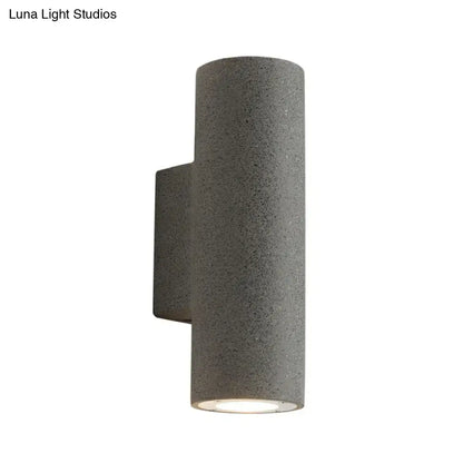 Gray textured cylindrical outdoor wall sconce with modern design and compact fixture height for minimalist terrazzo stairs
