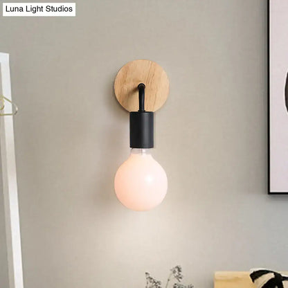Minimalist white and wood wall sconce with round wooden backplate black metal stem and direct wired electric light bulb