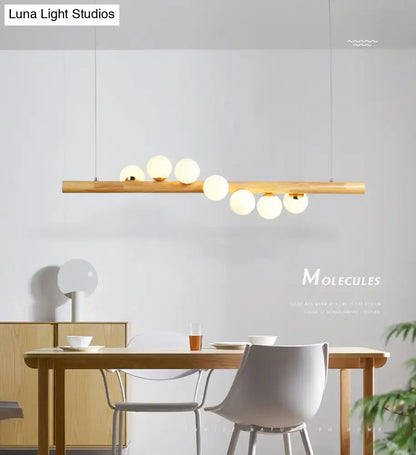 Minimalist wood and glass linear island pendant with slender wooden bar and frosted glass globes for kitchen lighting