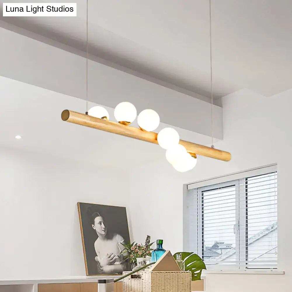 Minimalist linear island pendant with natural wood finish and five frosted glass globe bulbs for kitchen lighting