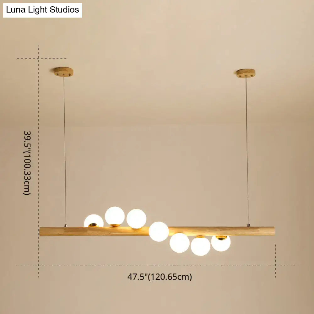 Minimalist wood and glass linear island pendant with warm wooden bar and spherical glass bulbs for kitchen lighting