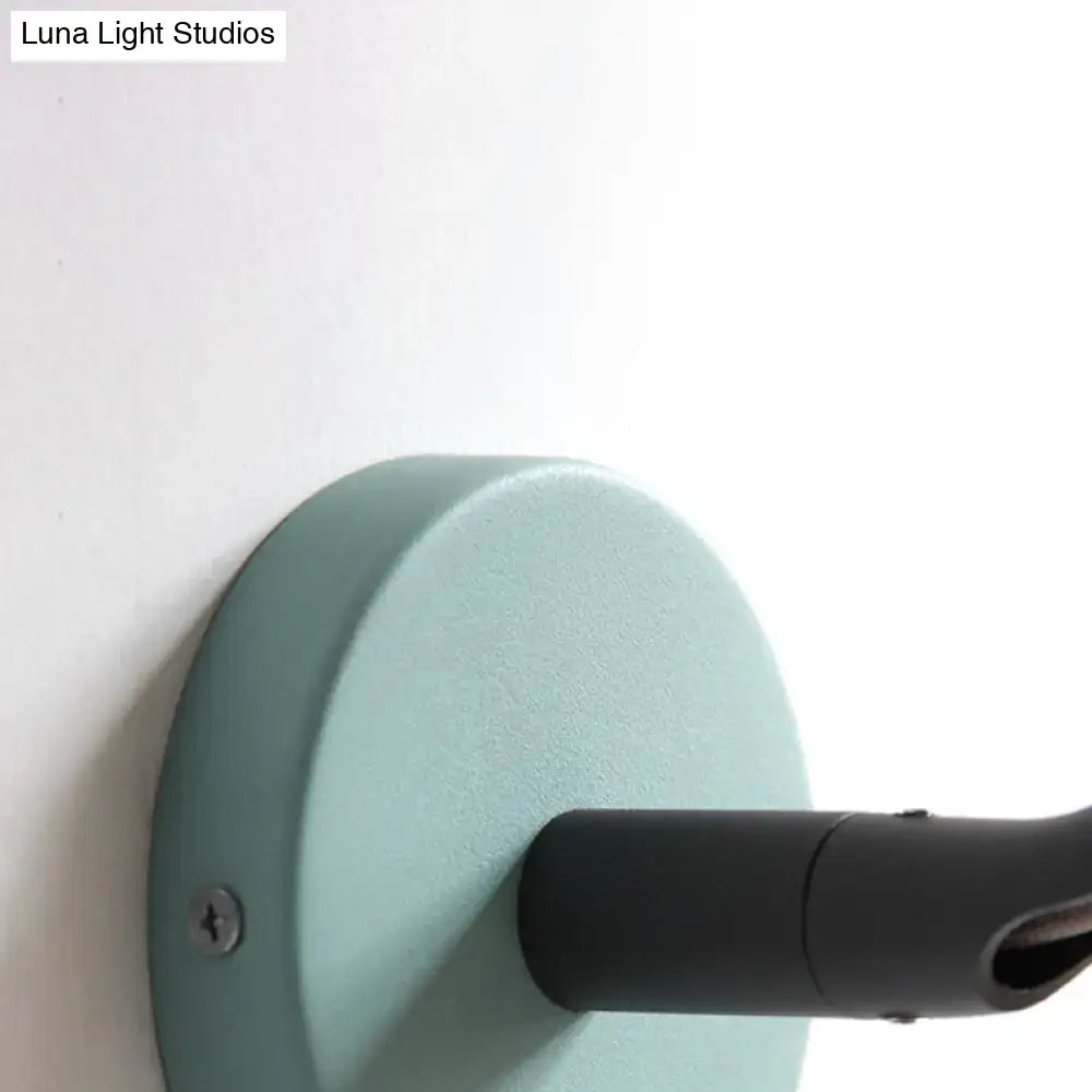 Minimalist matte mint green circular wall light fixture with black cylindrical arm designed for bathroom use