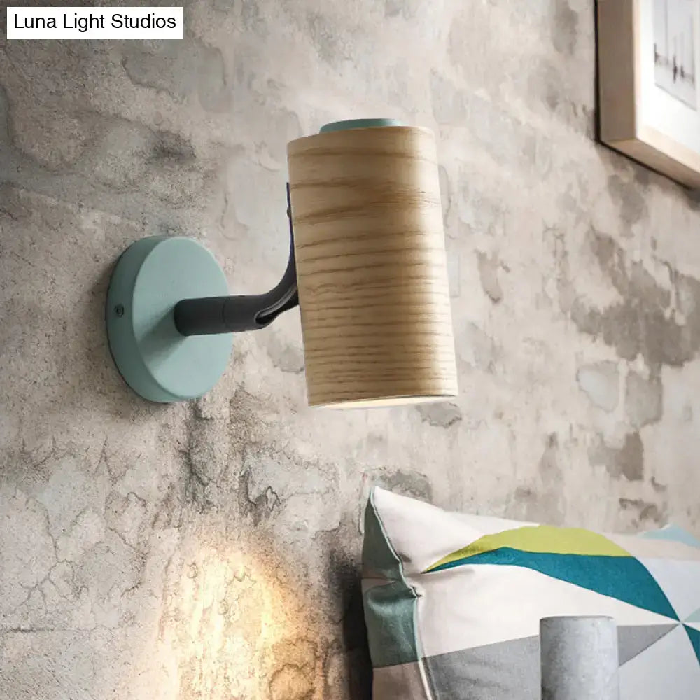 Minimalist wall light fixture with cylindrical wooden shade and mint green metal base for bathroom use