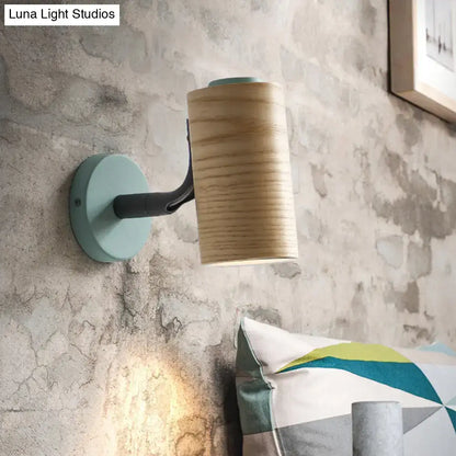 Minimalist wall light fixture with cylindrical wooden shade and mint green metal base for bathroom use