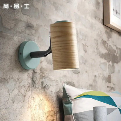 Minimalist wood wall light fixture with light blue circular base black arm and cylindrical natural wood shade for bathroom