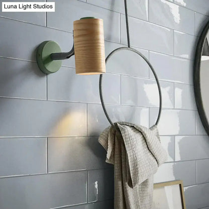 Minimalist wood wall light fixture with cylindrical wooden shade and green metal base paired with towel holder