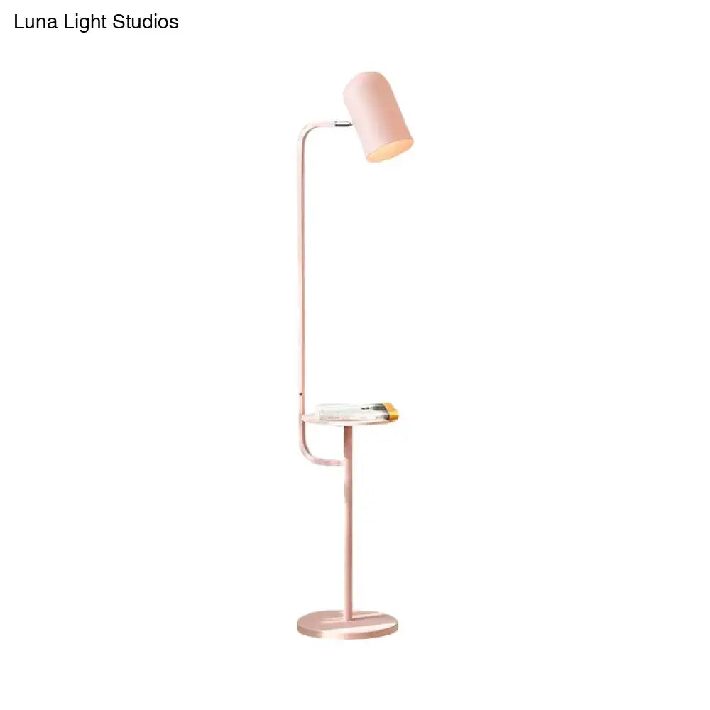 A sleek rose gold metal floor light with a cylindrical shade and integrated glass side table for reading