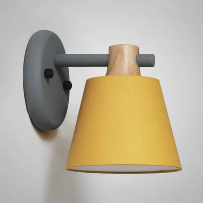 Yellow fabric bucket wall lamp mounted on gray metal arm with natural wood accent for nordic bedroom decor