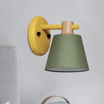 Yellow and wood-finished bucket wall lamp with matte olive green fabric shade for bedroom with wood accent