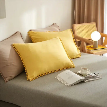 Bright yellow velvet pillow with decorative pom-pom border in mint green quilted duvet cover set with pom pom trim