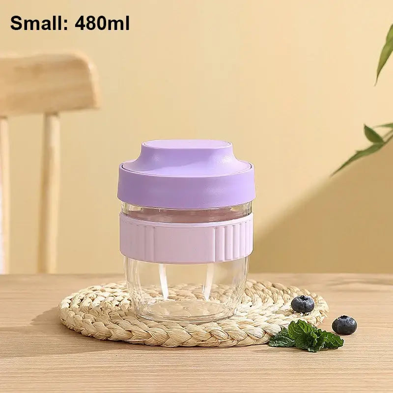 A clear glass decorbites breakfast cup with lavender lid and silicone grip band shown with mint green and yellow container
