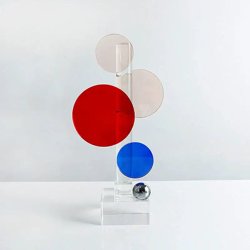 A modern abstract geometric crystal ornaments ring featuring red blue and beige translucent discs on a clear acrylic stand
