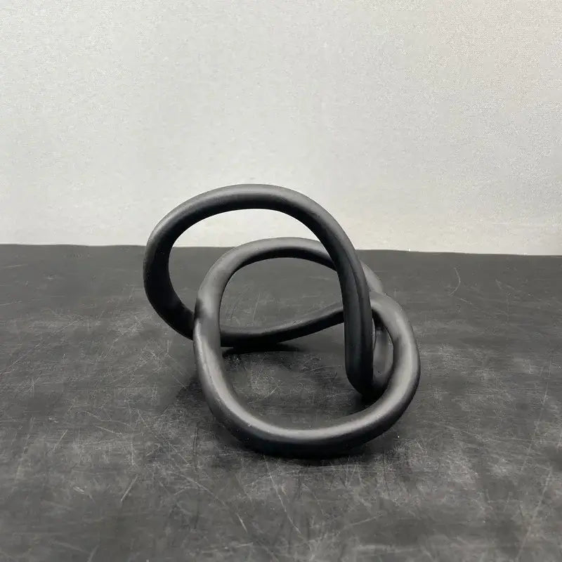 Black matte-finished ceramic modern abstract gold ring knot sculpture with interlocking circular loops for living room decor