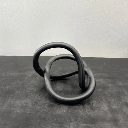 Black matte-finished ceramic modern abstract gold ring knot sculpture with interlocking circular loops for living room decor