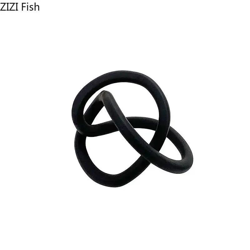 Black rubber ring with intertwined loops resembling a modern abstract gold ring knot sculpture for living room decor
