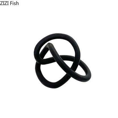 Black rubber ring with intertwined loops resembling a modern abstract gold ring knot sculpture for living room decor