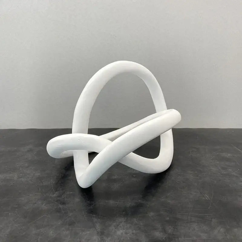 White smooth sculpted abstract knot sculpture resembling a gold ring knot for modern living room art decor