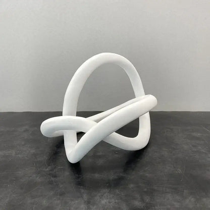 White smooth sculpted abstract knot sculpture resembling a gold ring knot for modern living room art decor