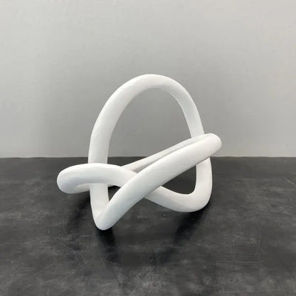 White smooth sculpted abstract knot sculpture resembling a modern gold ring knot for living room decor