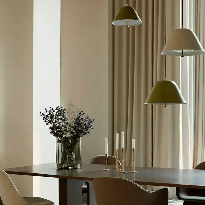 A clear glass vase with dried dark blue flowers on a table under a modern decorbites acrylic green dimmable pendant lamp