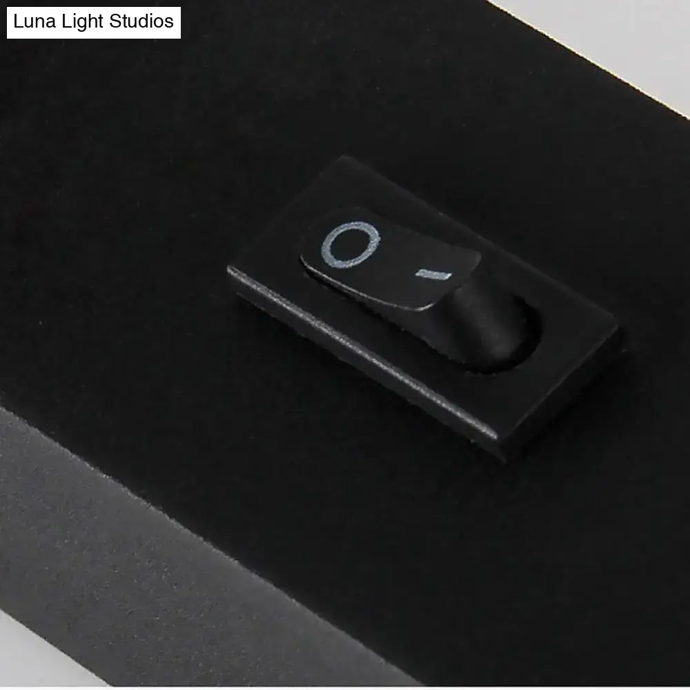 Black rectangular toggle switch with matte finish and white symbols on modern silver white led bedroom sconce lamp