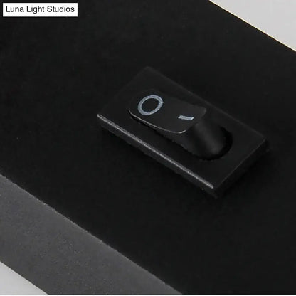 Black rectangular toggle switch with matte finish and white symbols on modern silver white led bedroom sconce lamp