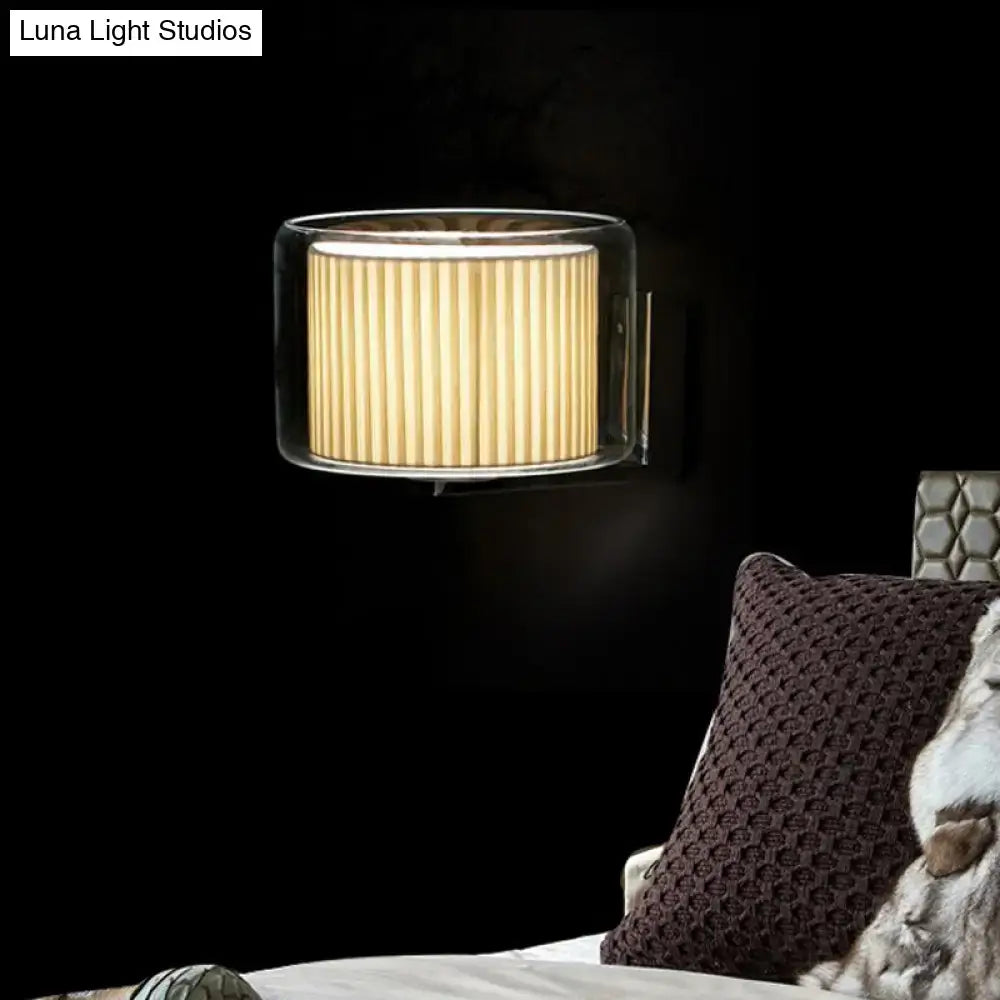 Modern amber and black wall lamp with a clear glass frame and warm pleated fabric shade for bedroom lighting