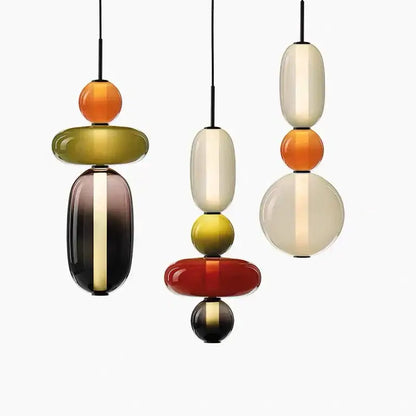 Three modern pendant lights with colorful glass ball orbs in amber cream red and olive green for dining room use