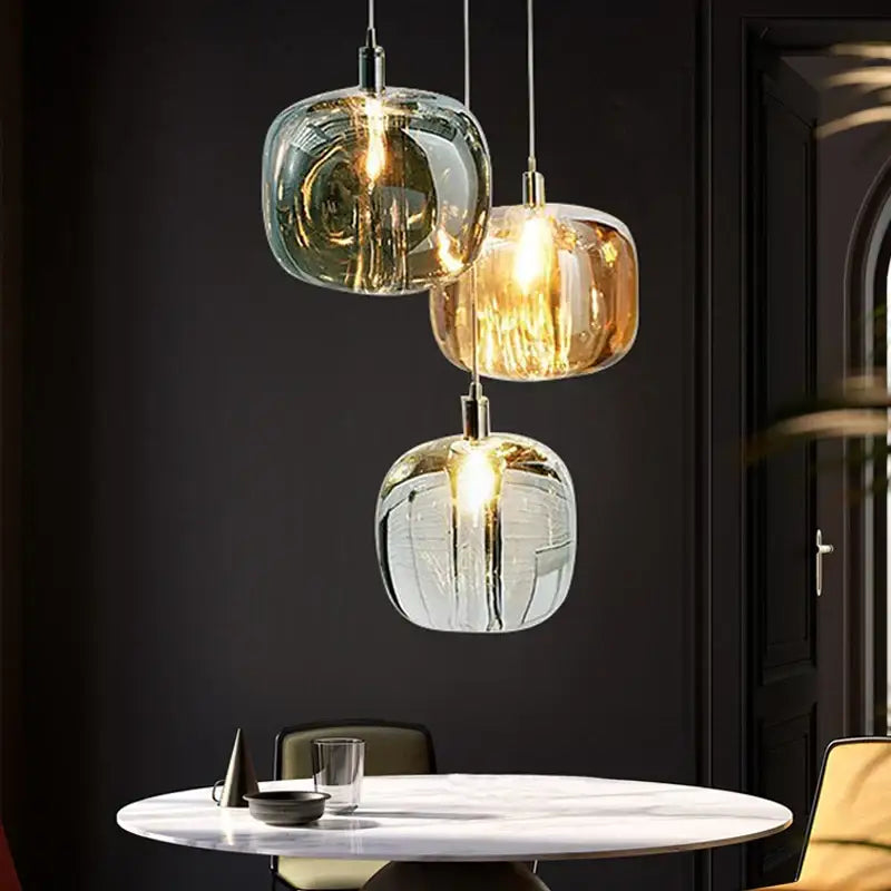 Modern amber and gold crystal led chandelier with three glass pendant lights in green amber and clear hues above marble table decorbites crystal led