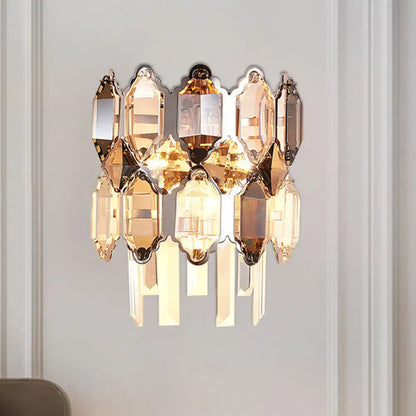 A modern amber and clear crystal wall sconce with cascading prisms and polished brass finish for staircase lighting