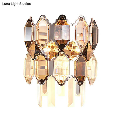 A modern amber and clear crystal wall sconce with faceted cascading glass and brass frame for staircase lighting