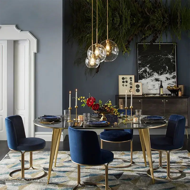 Navy blue velvet dining chairs with gold tone metal frames and circular bases complement modern amber glass ball led pendant light decorbites glass ball kitchen decor