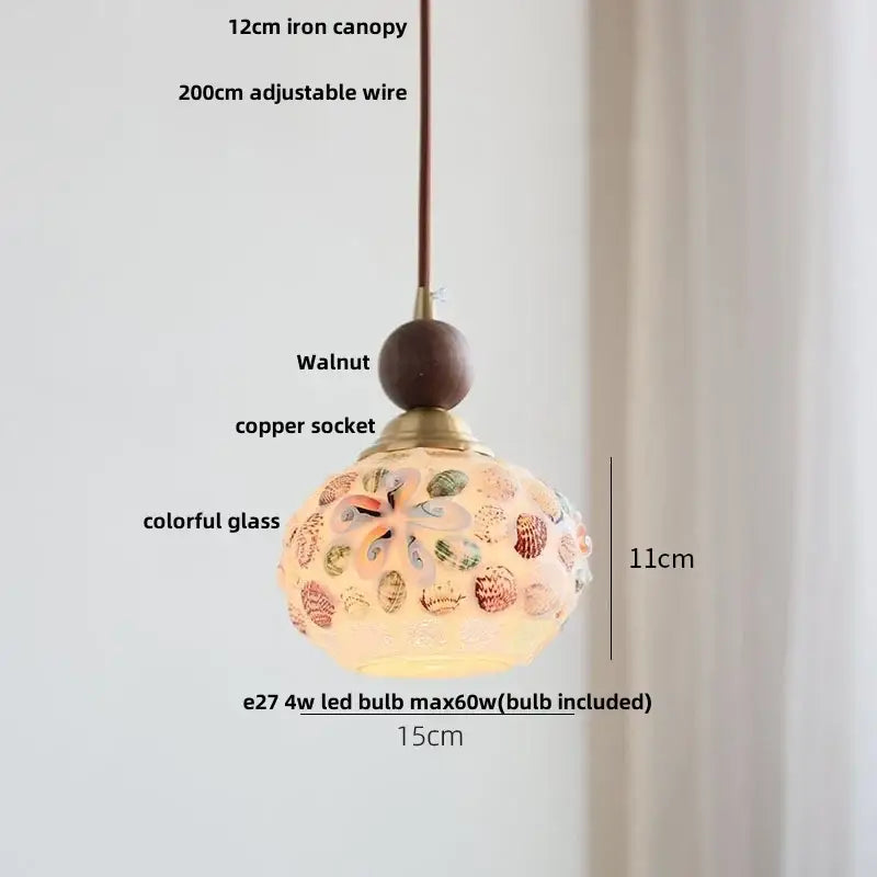 Modern amber glass led pendant light with a colorful spherical shade and shell patterns suspended from an iron canopy
