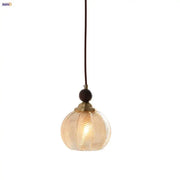Modern amber glass led pendant light featuring a warm-toned spherical glass led pendant with brass metal top and dark cord