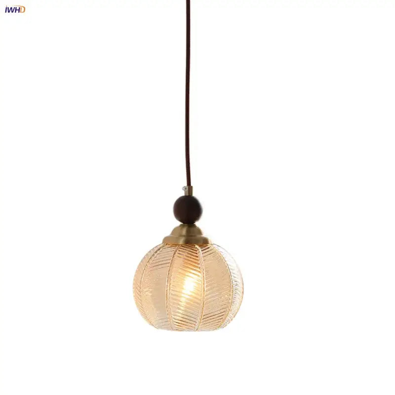 Modern amber glass led pendant light featuring a warm-toned spherical glass led pendant with brass metal top and dark cord