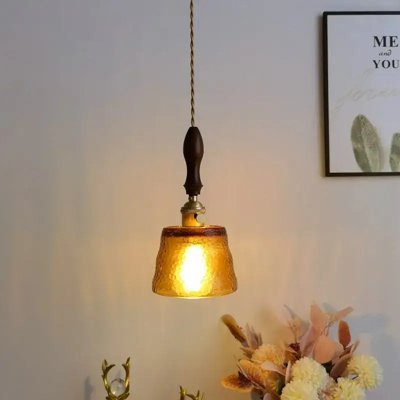 Modern amber glass pendant light with dark wood handle and hammered brass accents perfect for dining room decorbites decor