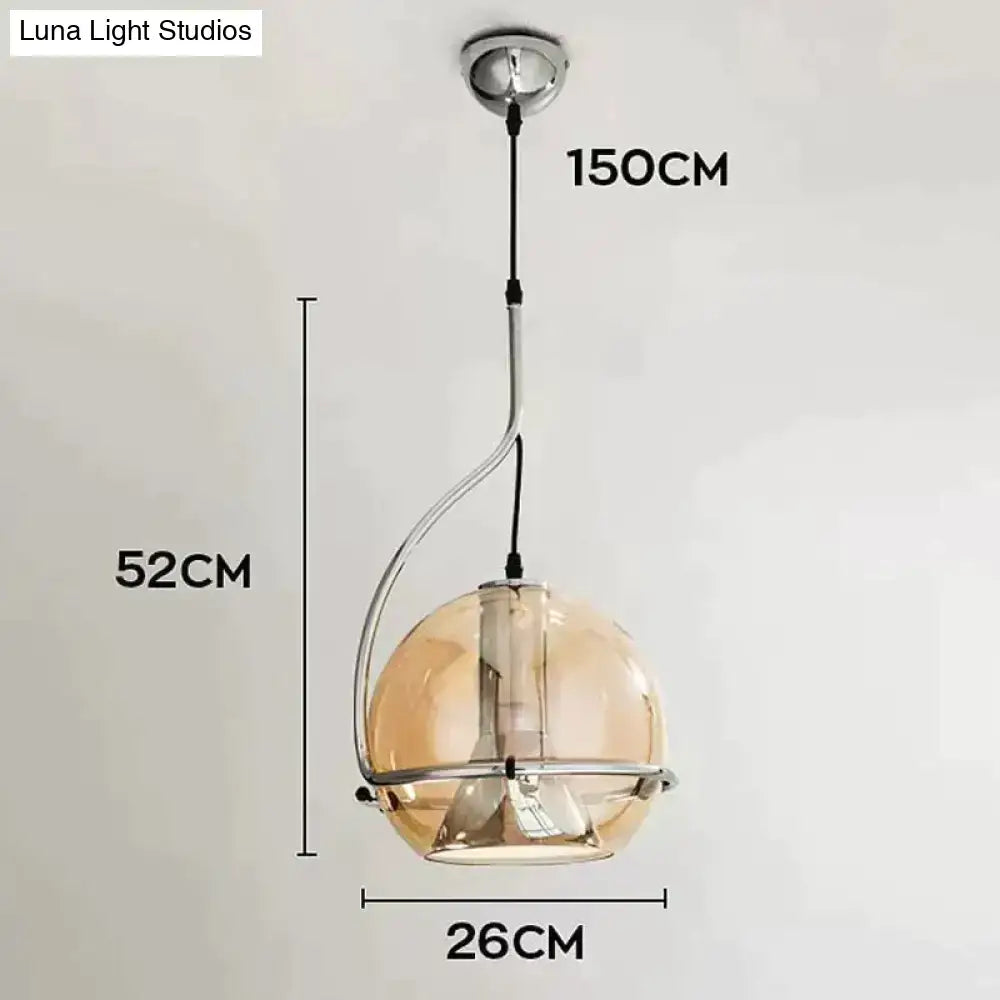 Modern amber glass pendant light with a curved chrome metal frame and amber-tinted glass globe for kitchen use