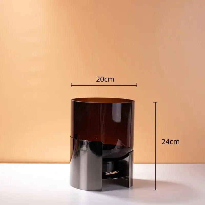 A modern decorbites amber glass trash can with a silver base and open bottom shelf for living room decor