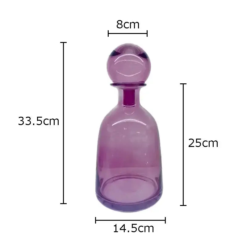 A translucent purple glass decanter with a rounded stopper and slender neck from decorbites amber glass vase trio
