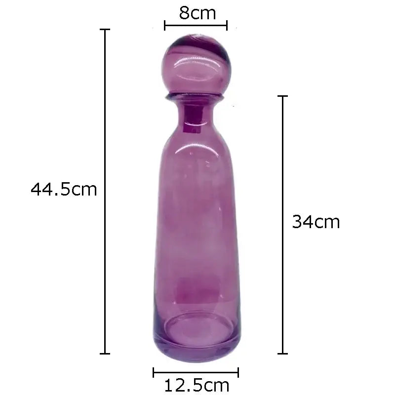 A translucent purple glass decanter with a rounded stopper and smooth tapered body for decorbites amber glass vase trio