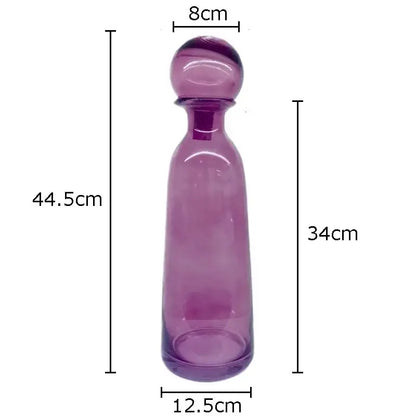 A translucent purple glass decanter with a rounded stopper and smooth tapered body for decorbites amber glass vase trio