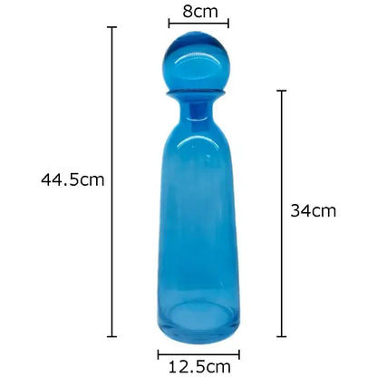 A translucent blue glass decanter with a rounded stopper and smooth tapered body in a decorbites amber glass vase trio set