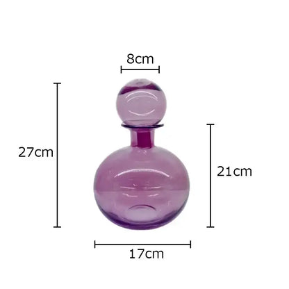 A translucent purple glass decanter with a rounded body and stopper from the decorbites amber glass vase trio collection