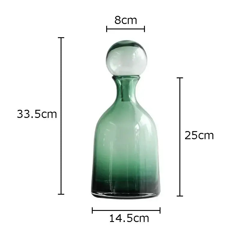 A tall slender decorbites amber glass decanter with gradient green tint and clear spherical stopper for living room hydroponics