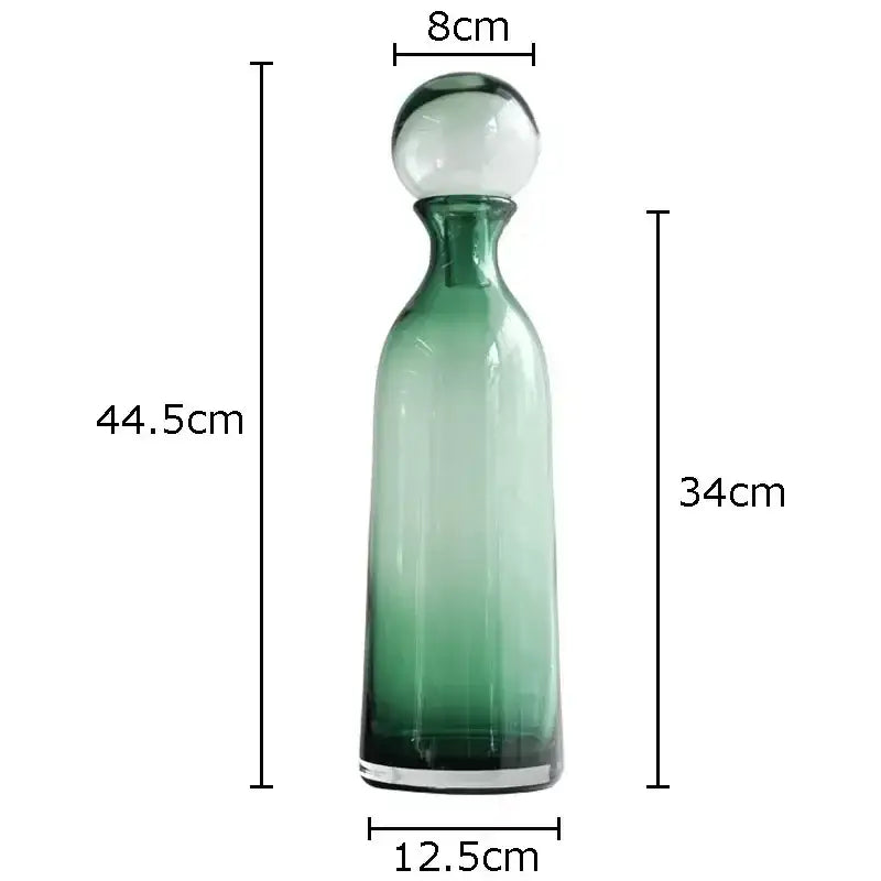 A tall slender green glass decanter with frosted white stopper and clear base in decorbites amber glass vase trio hydroponic set
