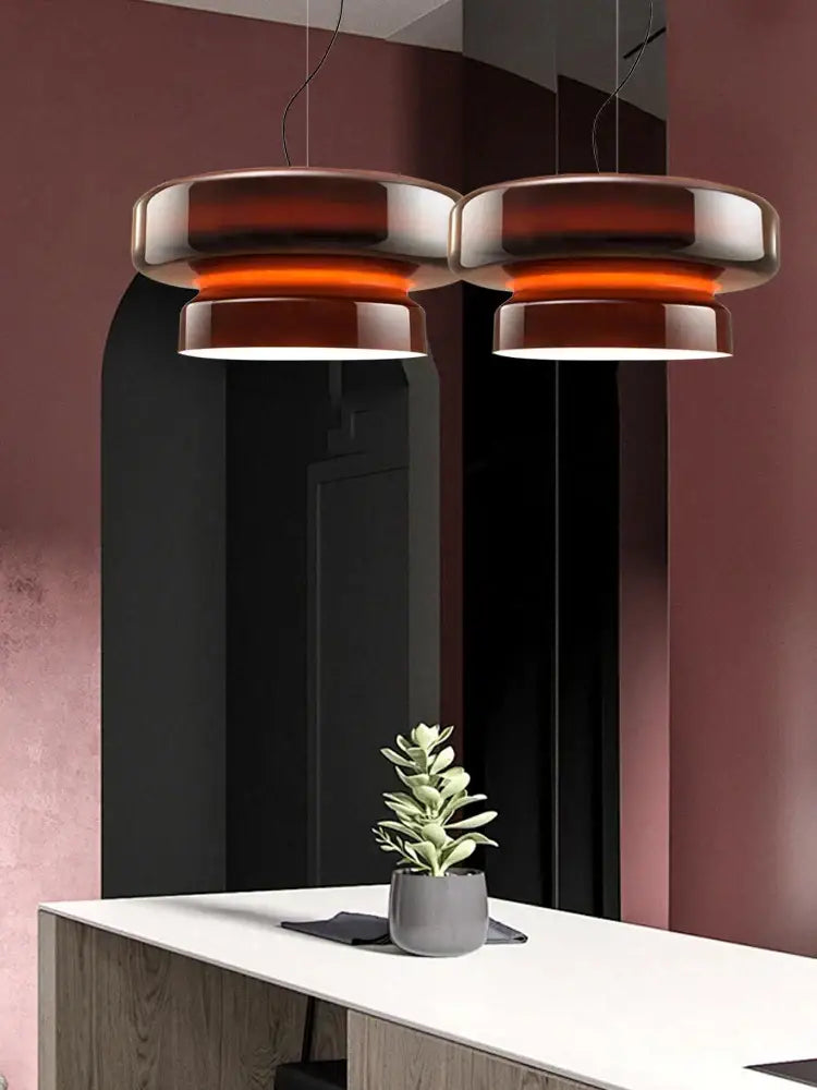 Two modern tiered pendant lights with glossy amber green glass finish hang above the dining room counter decorbites amber green