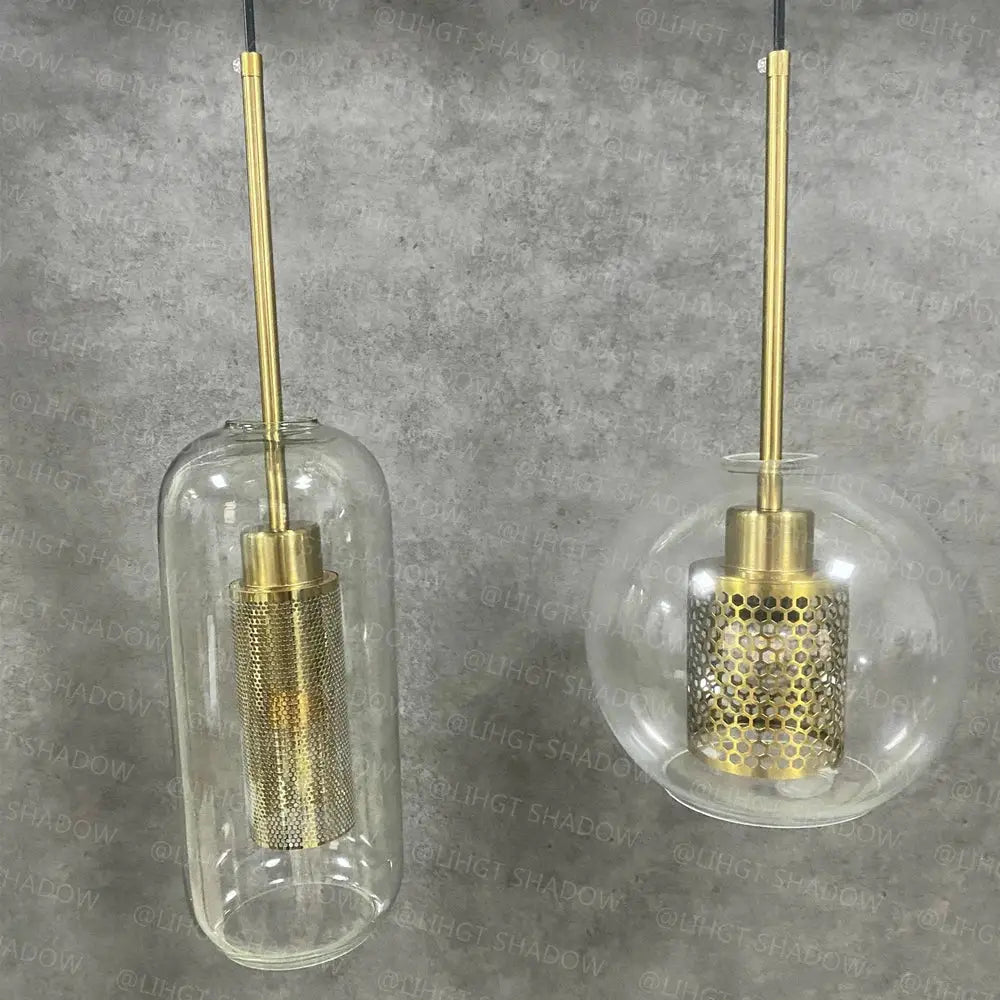 Two modern brass-finished pendant lights with cylindrical and spherical decorbites glass ball led enclosures in amber hue
